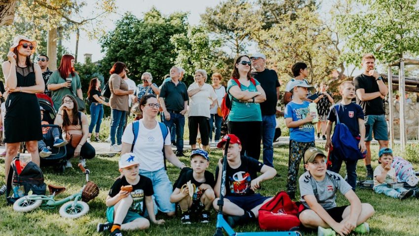 A diverse group of people enjoying a sunny day at an outdoor community event in a park setting.